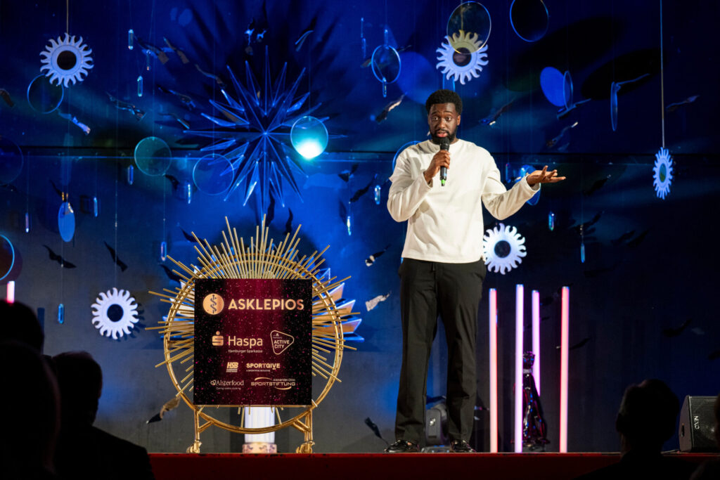 Comedian Eliab Bashey auf der Bühne beim Hamburger SportTalent 2026 in der Aula der Schule Alter Teichweg