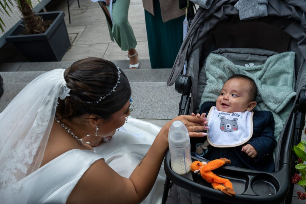 Braut mit Baby am Kinderwagen