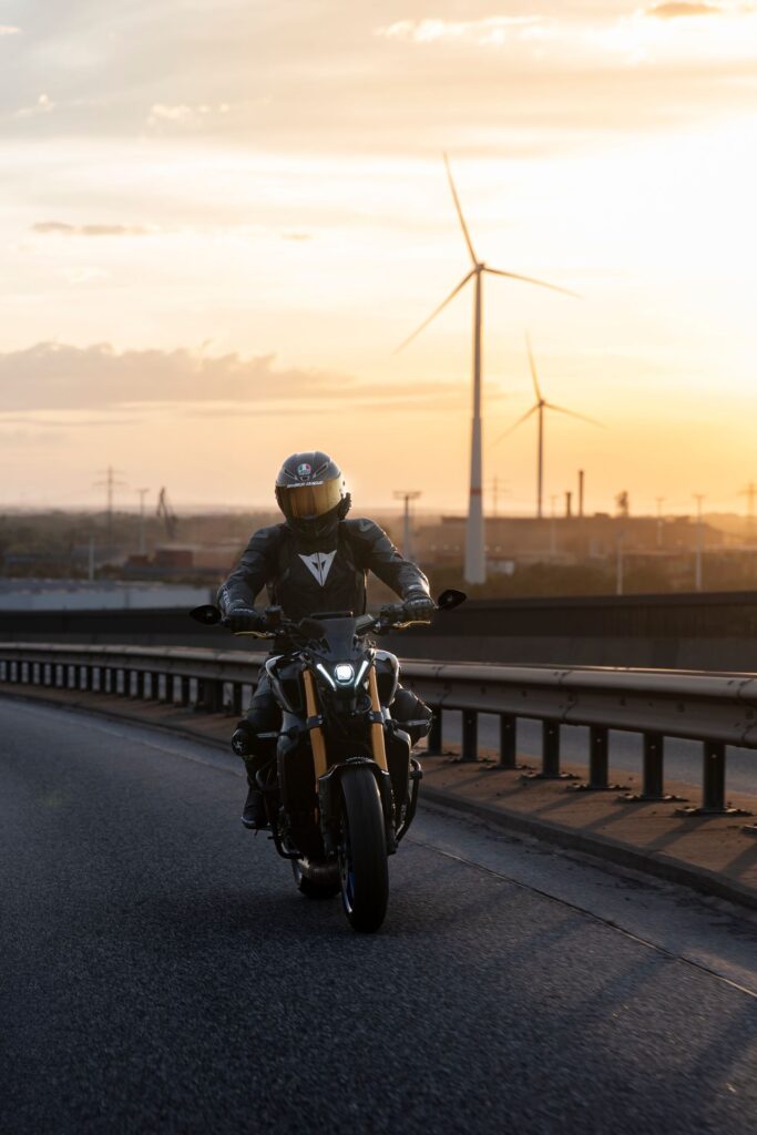 Motorradfahrer im Sonnenuntergang vor Windrädern
