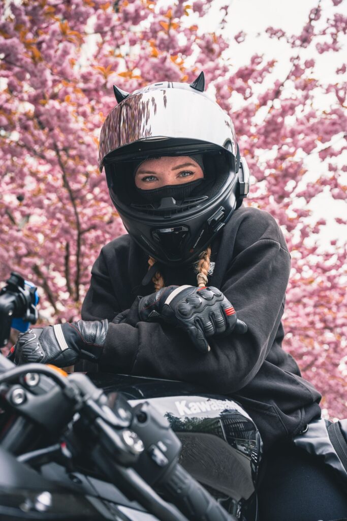Porträt einer Motorradfahrerin mit Helm vor Kirschblüten