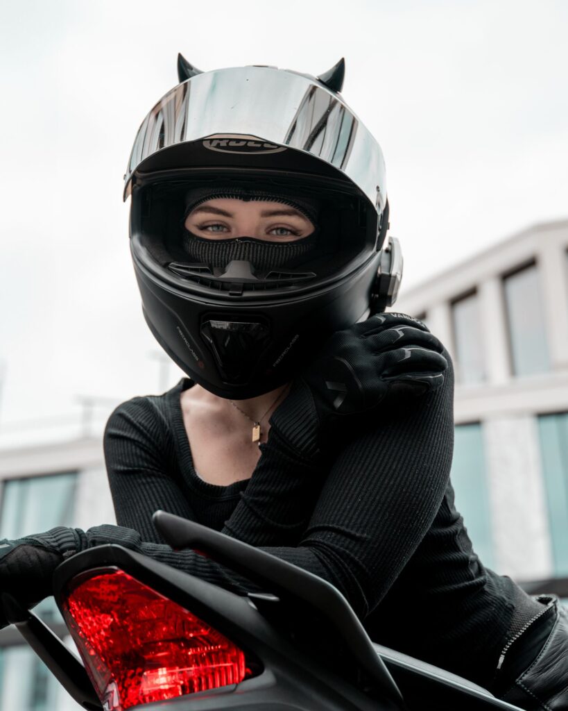 Porträt einer Motorradfahrerin mit Helm im roten Rücklicht